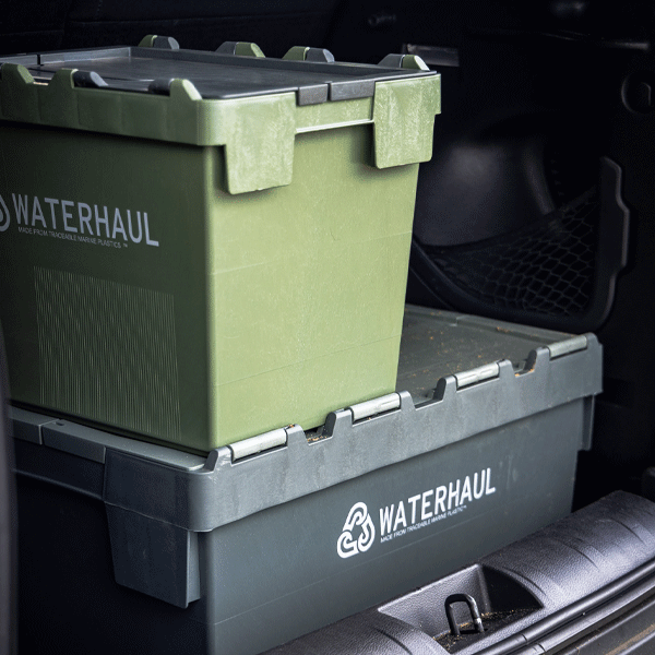 Two WATERHAUL storage containers stacked inside a vehicle.