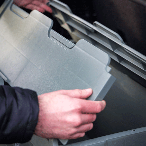 Person opening a green storage box inside a vehicle