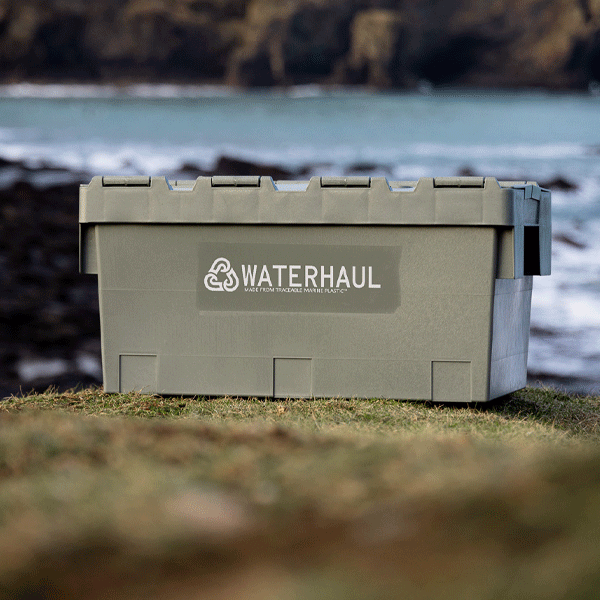Green storage box with 'Waterhaul' logo on a grassy area near a body of water.