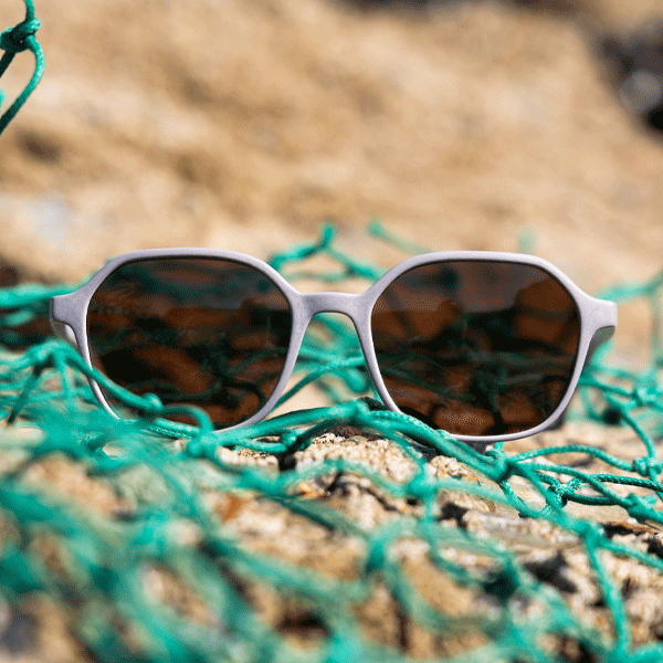Sunglasses with reflective lenses on a textured surface with green fishing net