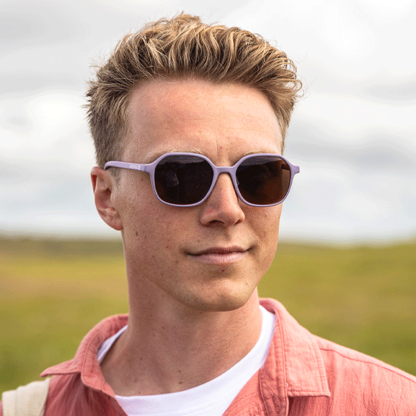 Man wearing heather coloured sunglasses against a natural background