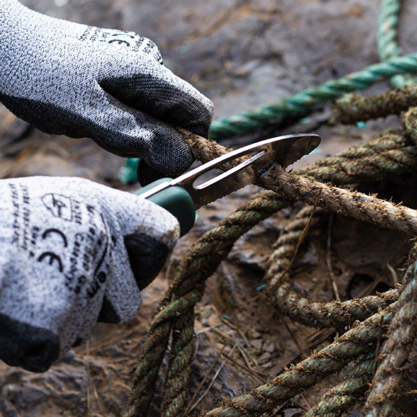 Pocket knife with blunt tip and serrated edge being used to cut maritime ropes