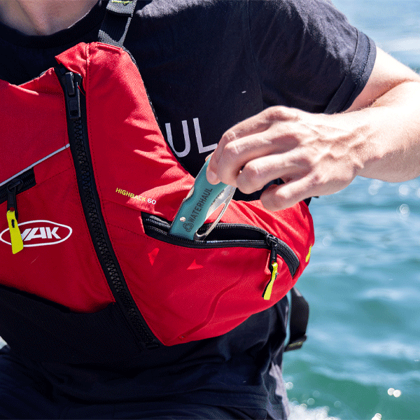 Person putting a green pocket knife in a buoyancy aid pocket
