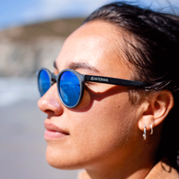 Person wearing blue sunglasses with a blurred outdoor background