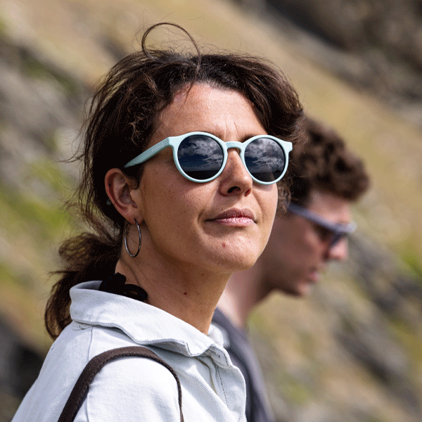 Woman wearing blue sunglasses against a scenic background