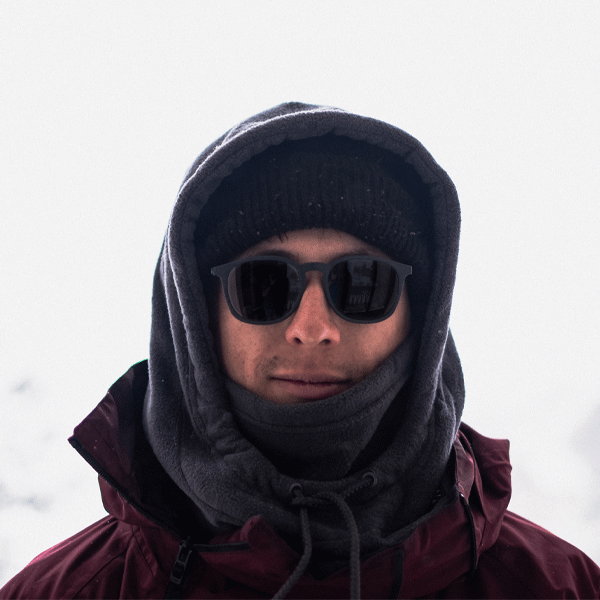 Man wearing sunglasses and winter clothing against a snowy background