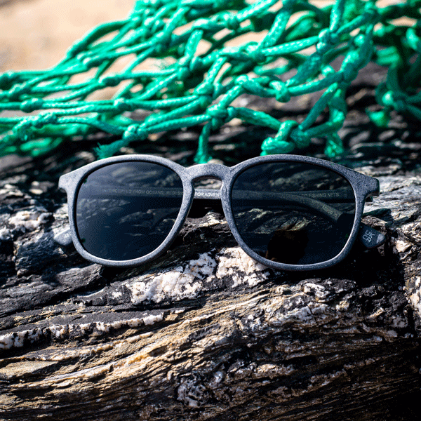 Sunglasses against a rocky background with green fishing nets.