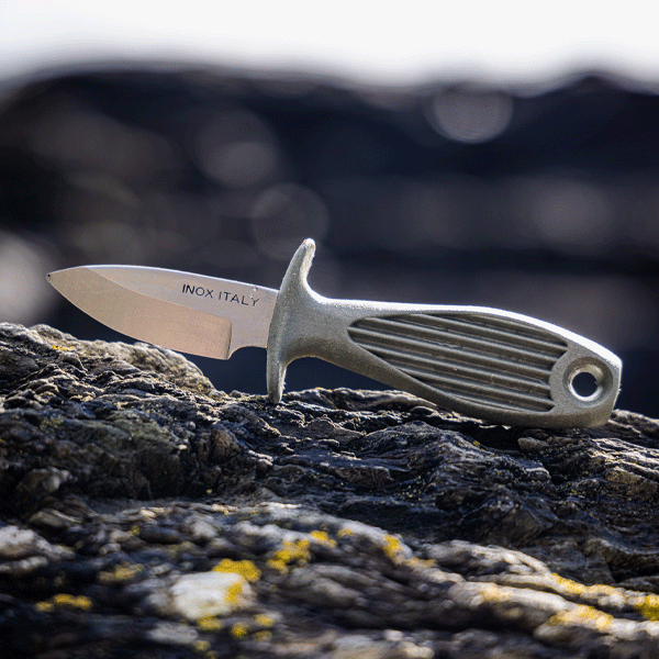 Oyster shucking knife with silver blade and green recycled handle on rocky surface
