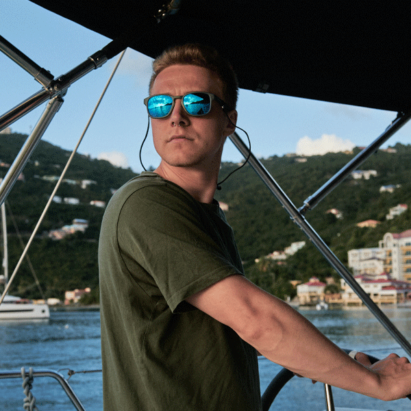 Man wearing sunglasses on a boat with a scenic background