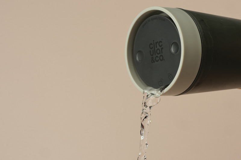 Green and grey cup with 'circular&co' branding on a beige background