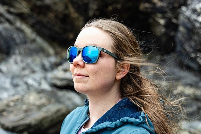 Woman wearing reflective sunglasses with a rocky background