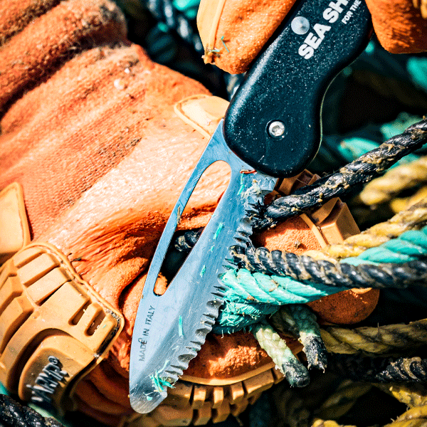 Fishing knife with 'Sea Shepherd' branding on a background of orange boots and ropes.