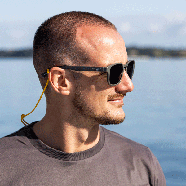 Man wearing sunglasses with a blurred background of water and sky